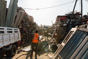 Workmen standing near pile of metal scrap